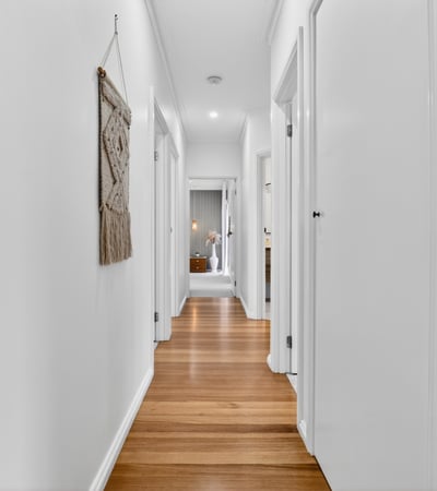 Bright and inviting hallway featuring warm wooden floors and a modern, open layout.