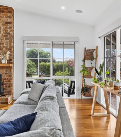 Bright, inviting living space featuring a cozy fireplace and panoramic views of the surrounding gardens.