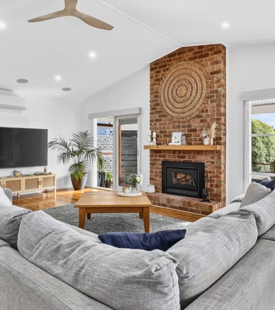 Spacious living area features a cozy fireplace, ample natural light, and direct access to outdoor views.
