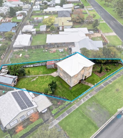 Spacious corner lot with potential for development, featuring a two-story home and ample outdoor space.