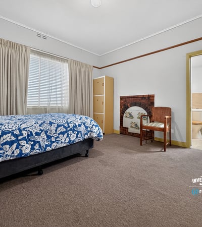 Spacious bedroom featuring natural light, a cozy seating area, and convenient access to an ensuite bathroom.
