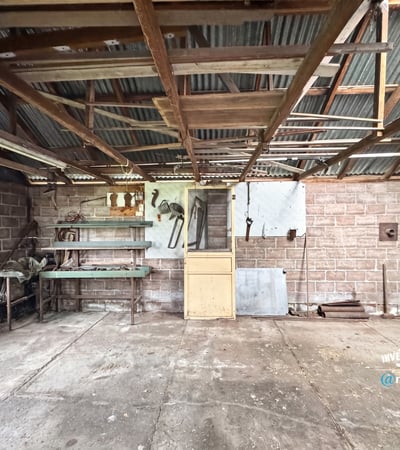 Spacious workshop with ample storage, ideal for projects or hobbies, featuring sturdy structures and natural light.