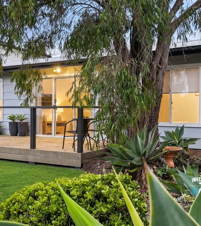 Bright and inviting home featuring a spacious deck, lush landscaping, and modern living spaces.