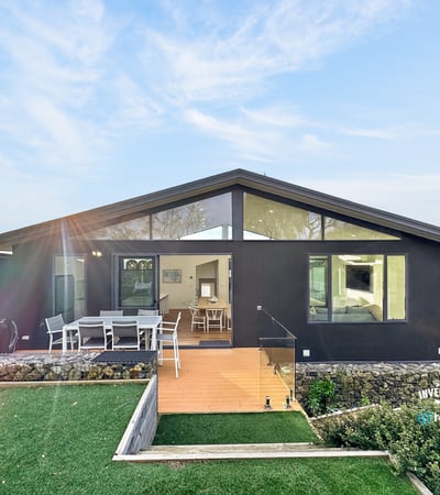 Contemporary home featuring expansive windows and a spacious outdoor deck, perfect for entertaining and relaxation.
