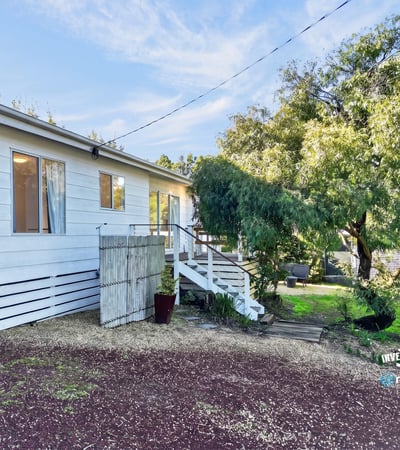 This inviting home features a spacious yard and a welcoming entrance surrounded by lush greenery.