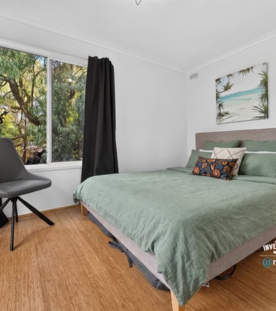 Bright bedroom featuring large window with natural light, contemporary furnishings, and a relaxed, inviting atmosphere.