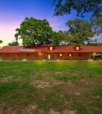Discover this spacious home set on a sprawling green lot, featuring a distinctive red roof and open outdoor space.