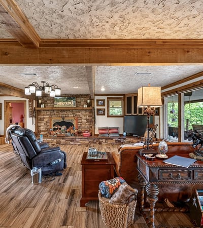Spacious living area with a rustic fireplace, natural light, and inviting views of the outdoors.