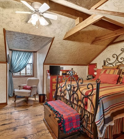 Cozy loft bedroom featuring exposed beams, a unique design, and ample natural light from large windows.