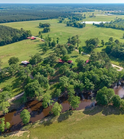 Expansive rural property with lush greenery, waterways, and multiple outbuildings, ideal for diverse development opportunities.
