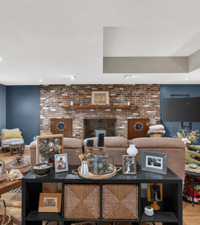 Spacious living area featuring exposed brick accents, ample natural light, and versatile entertainment options.