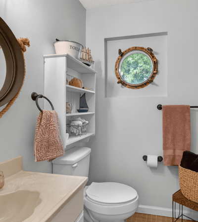 Bright bathroom featuring modern fixtures, a unique round window, and ample storage for convenience.