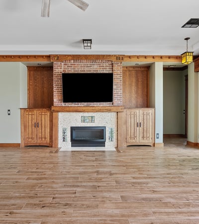 A beautifully designed living room with custom oak built ins, brick fireplace surround, and durable wood look flooring. Ideal for relaxing or hosting in this thoughtfully designed Phoenix residence.