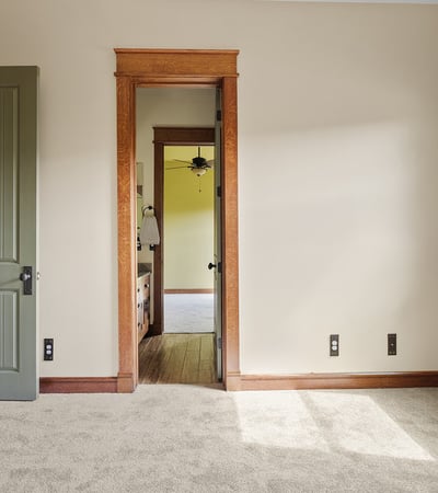 Bright bedroom with soft carpeting, wood-trimmed windows, and classic design elements. A comfortable space filled with natural light and timeless appeal.