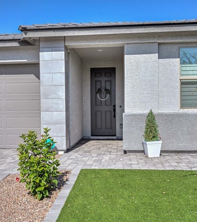 Enter through a clean-lined portico with upgraded trim, neutral tones, and thoughtfully landscaped greenery in front.