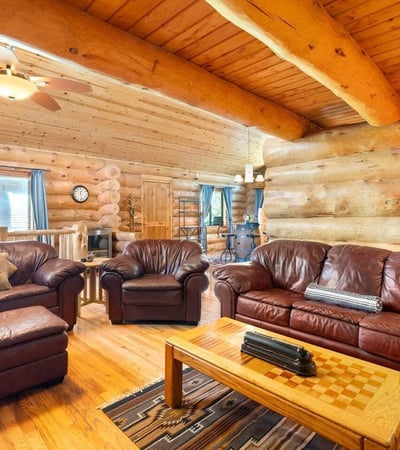 Comfortable living space framed by log walls and natural wood finishes, creating a warm and inviting lodge-inspired atmosphere.