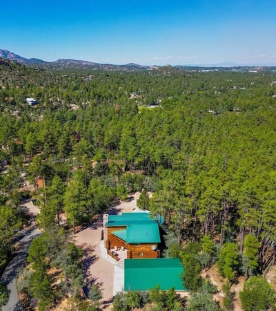 Broad aerial view showcasing dense pine forest and rolling terrain. The property s location offers scenic beauty, quiet surroundings, and a connection to nature unique to Prescott living.