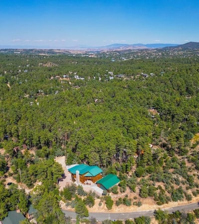 Panoramic aerial image capturing miles of forest and valley beyond the home. This view highlights the elevated position and scenic beauty that define this exceptional Prescott property.