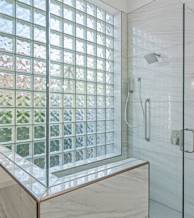 Spacious glass shower with rainfall fixture, handheld sprayer, and sleek tilework offers modern luxury.