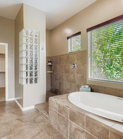 En-suite bath includes a soaking tub, walk-in shower, and oversized windows, creating a luxurious retreat at home.