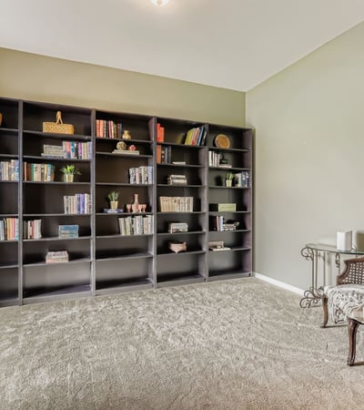 The front den provides built-in shelving and natural light, ideal for a private office, home library, or additional living space.