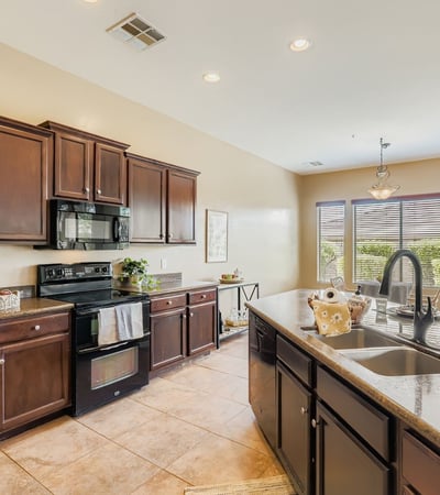 Bright windows frame backyard views from the gourmet kitchen, complete with granite counters, sleek appliances, and warm cabinetry.