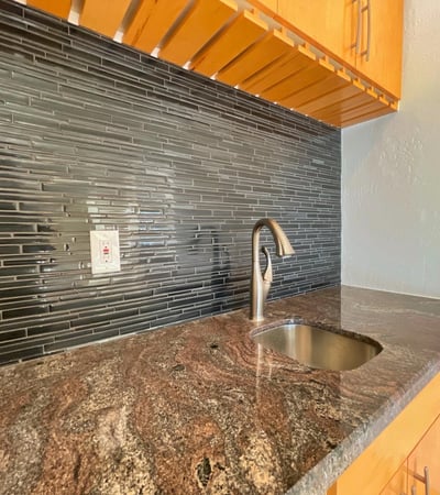 Contemporary wet bar accented with granite surfaces and glass-tile details. Perfectly suited for stylish entertaining and everyday convenience.