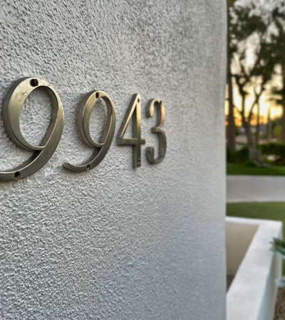 Polished metal address numbers accentuate the sleek stucco exterior, blending modern style with simplicity.