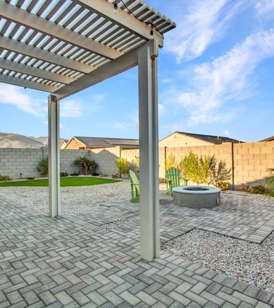 A cozy fire pit surrounded by pavers and desert landscape creates an ideal gathering place in this serene Litchfield Park backyard.