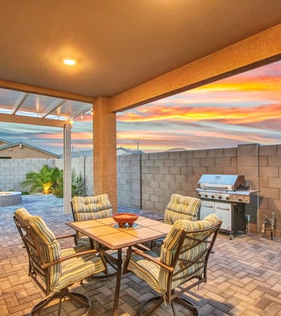 This twilight patio scene showcases a relaxing outdoor dining area with updated pavers, soft lighting, and easy access to the backyard. A perfect extension of the home s modern upgrades in Litchfield Park.