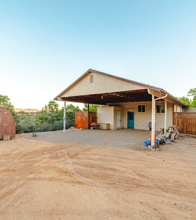This large covered carport provides shade, storage, and easy home access, ideal for desert living. Additional structures support tools, outdoor gear, and practical everyday use.