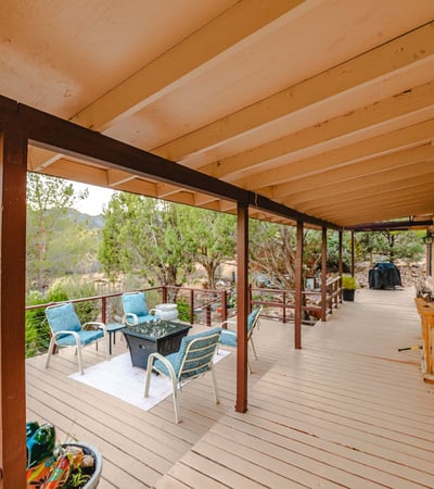 This deck's outdoor lounge area offers a welcoming place to gather, relax, and enjoy views of desert terrain and rolling hills in the distance.