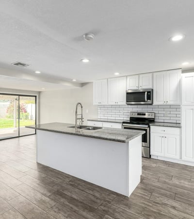 Beautiful kitchen featuring granite countertops, a large island with seating, stainless steel appliances, subway tile backsplash, and white cabinetry perfect for cooking and hosting in Phoenix.