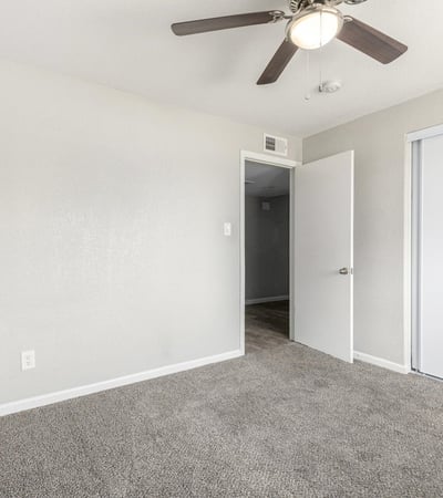 Secondary bedroom view showing plush carpet, bright window light, and closet storage move-in ready comfort in this Phoenix home.