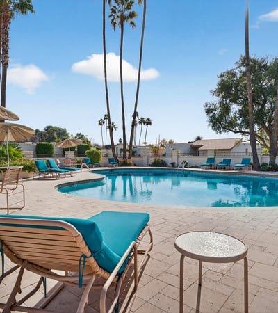 Beautifully maintained community pool surrounded by palm trees and lounge areas, offering a true resort-style atmosphere.