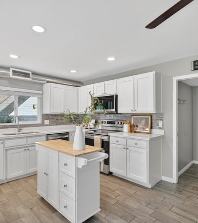 Updated kitchen showcasing white cabinetry, contemporary backsplash, stainless appliances, and abundant counter space.