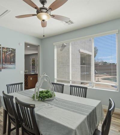 Dining space overlooking the backyard retreat with pool and spa, allowing natural light to fill the room and connecting indoor dining with outdoor living.