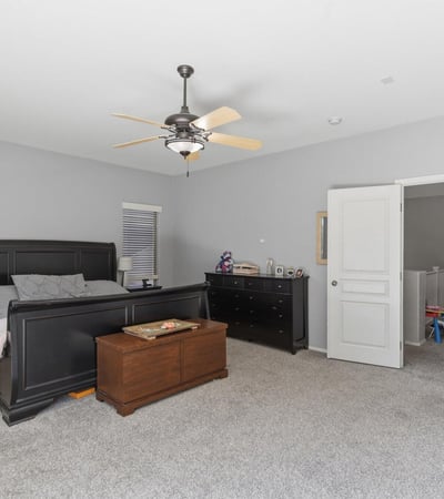 Generous primary suite featuring plush carpeting, large windows, ceiling fan, and ample space for bedroom furniture, creating a peaceful retreat in this Queen Creek property.