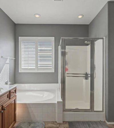 Spacious primary bathroom featuring a soaking tub, separate glass shower, and tile flooring designed for comfort and convenience.
