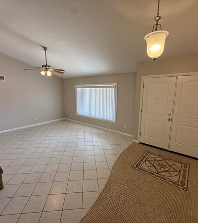 Spacious Glendale living room featuring tile flooring, neutral tones, vaulted ceilings, and a classic stone fireplace. The open design provides a comfortable gathering space with plenty of natural light.