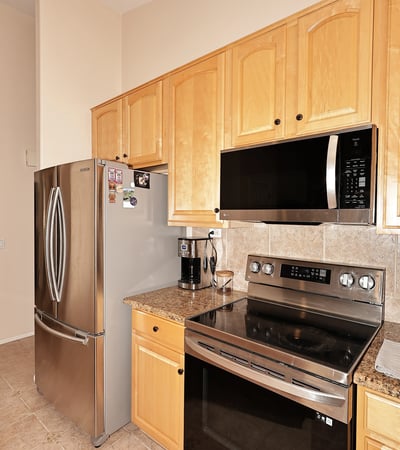 Cooking area with stainless steel range, built-in microwave, and tiled backsplash. This Phoenix home includes updated features and efficient layout.