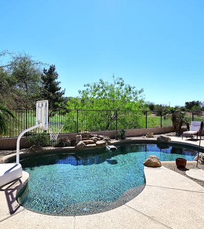 Backyard pool with unobstructed golf course views and desert landscaping. This Phoenix home offers privacy, open space, and resort-style outdoor features.