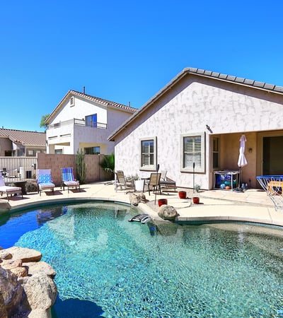 Backyard with Pebble Tec pool, rock waterfall feature, and spacious patio. This Phoenix home highlights outdoor living with low-maintenance desert landscaping.