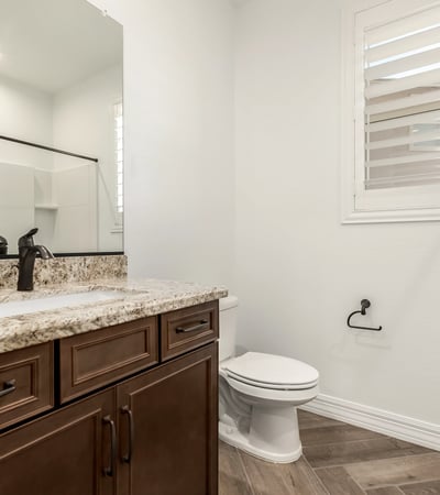 Guest bathroom featuring granite counters, wood cabinetry, and modern fixtures, blending style and everyday functionality.