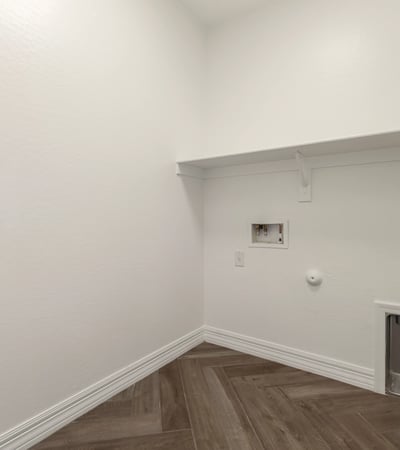 Dedicated laundry area with storage shelving and utility hookups, designed for efficient household tasks.