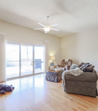 Open-concept living area with hardwood floors, ceiling fan, and large sliding doors leading to the backyard patio for indoor-outdoor living.