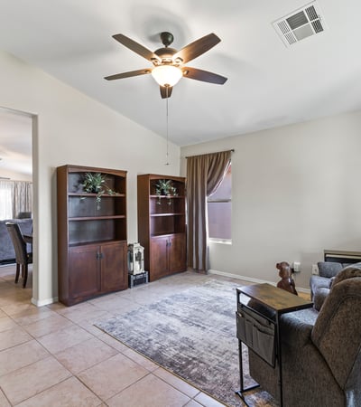 Spacious front living area with tile flooring, ceiling fan, and natural light. A versatile space perfect for relaxing or hosting guests.