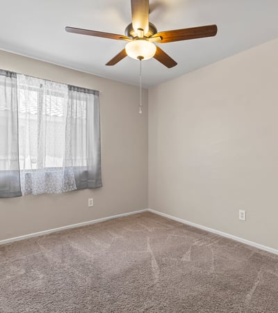 Comfortable bedroom with soft carpeting, ceiling fan, and closet space ideal for guests or family members.