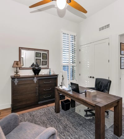 Private office with plantation shutters, natural light, and wood floors, ideal for working from home in this Phoenix property.