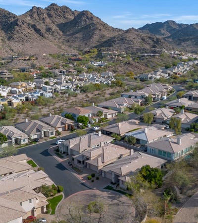 Wide aerial view of a Phoenix neighborhood set against picturesque mountains, highlighting location, nearby homes, and desert surroundings.